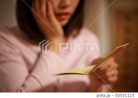 貯金通帳を見て悩む女性 50531125