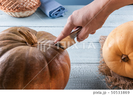 Cutting whole orange pumpkin with metal knife 50533869