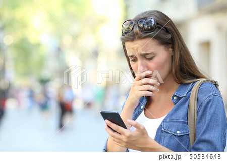 Sad girl checking phone content in the street Sad girl checking phone content in the street 50534643