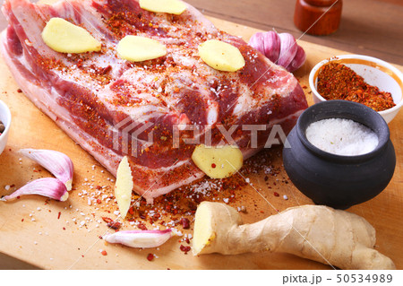 Raw fresh meat, uncooked lamb or beef ribs with pepper, garlic, salt and spices on dark stone 50534989