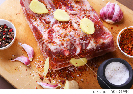 Raw fresh meat, uncooked lamb or beef ribs with pepper, garlic, salt and spices on dark stone 50534990
