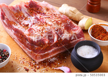 Raw fresh meat, uncooked lamb or beef ribs with pepper, garlic, salt and spices on dark stone 50535003