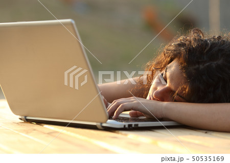 Overworked tired woman resting over a laptop Overworked tired woman resting over a laptop 50535169