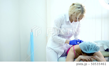 doctor neurologist makes an injection to the patient in the back along the spine doctor neurologist makes an injection to the patient in the back along the spine 50535461
