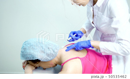 doctor neurologist makes an injection to the patient in the back along the spine doctor neurologist makes an injection to the patient in the back along the spine 50535462