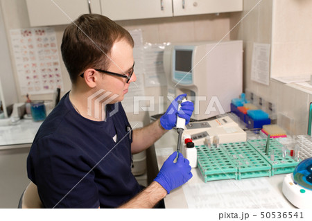 laboratory assistant analyzing a blood sample laboratory assistant analyzing a blood sample 50536541