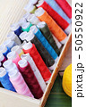 Colorful thread for sewing on wood background 50550922