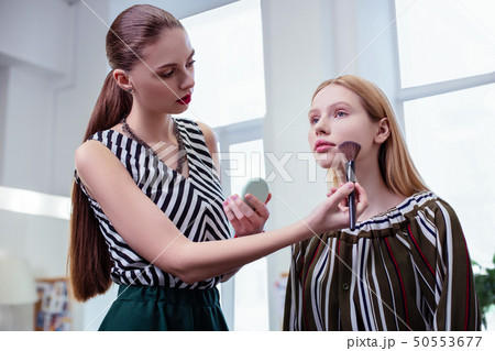 Nice long haired visagiste applying facial powder Nice long haired visagiste applying facial powder 50553677
