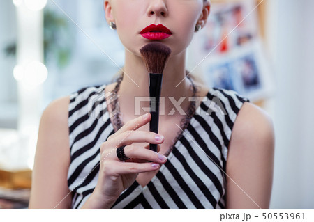 Nice good looking woman touching her chin with a makeup brush 50553961