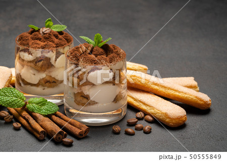 Classic tiramisu dessert in a glass and savoiardi cookies on dark concrete background Classic tiramisu dessert in a glass and savoiardi cookies on dark concrete background 50555849