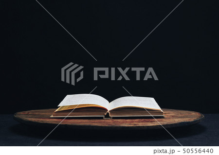 One open old book on a round wooden table. One open old book on a round wooden table. 50556440