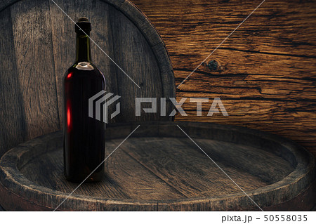 Red wine bottle on a old barrel table background 50558035
