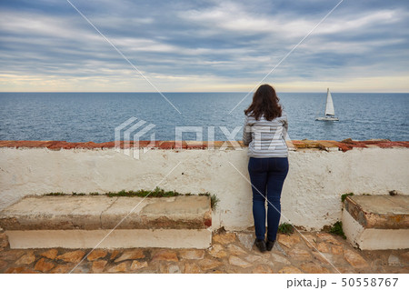 Woman looking at infinite sea and sailboat Woman looking at infinite sea and sailboat 50558767