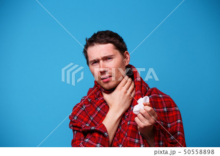 Sick man wrapped in a blanket is holding his throat. Concept of sore throat 50558898