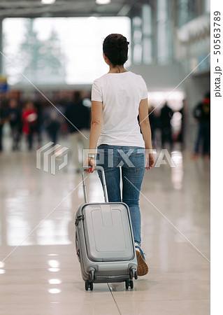young woman walking with suitcase in an airport young woman walking with suitcase in an airport 50563789