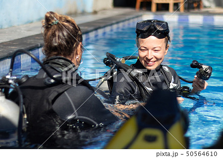 Woman getting first experience with scuba diving under the guidance of experienced recreational 50564610