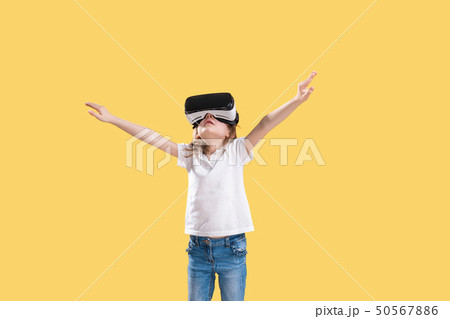 Girl 7 y.o in formal outfit wearing VR glasses putting hands out in excitement isolated on yellow Girl 7 y.o in formal outfit wearing VR glasses putting hands out in excitement isolated on yellow 50567886