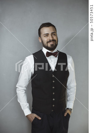 Smiling man in black vest and bow tie 50573451
