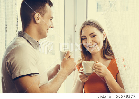 young couple drinking tea or coffee at home 50579377