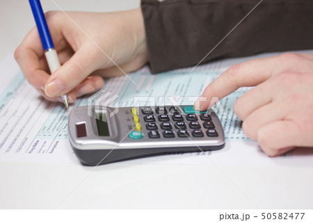 Filling income tax forms with calculator and pen Filling income tax forms with calculator and pen 50582477
