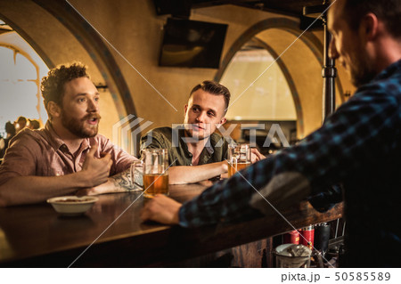 Cheerful friends drinking draft beer in a pub 50585589