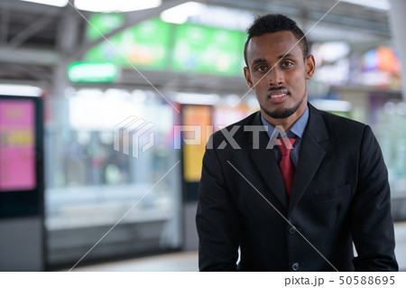 Happy young African businessman waiting at the train station Happy young African businessman waiting at the train station 50588695