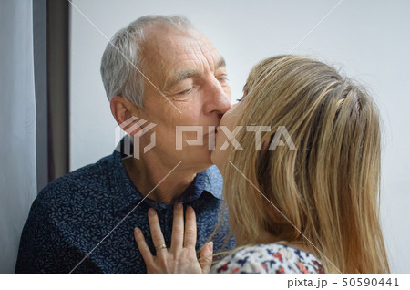 Lovely Couple with Age Difference Kissing inside the House During Spring Time. 50590441