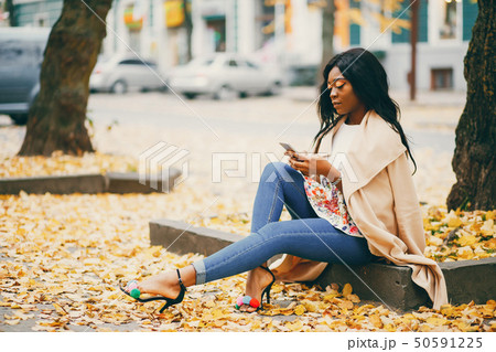 Black woman sitting in a autumn city 50591225