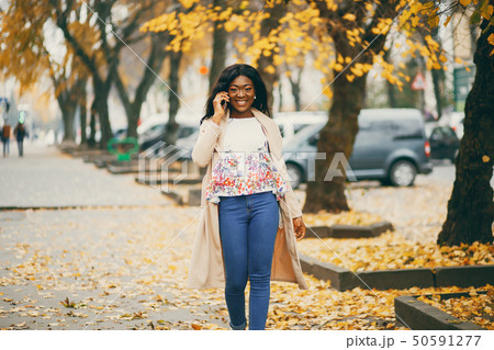 Black woman standing in a autumn city Black woman standing in a autumn city 50591277