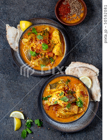 INDIAN FOOD. Traditional KERALA FISH CURRY with naan bread, gray plate, black background INDIAN FOOD. Traditional KERALA FISH CURRY with naan bread, gray plate, black background 50592081