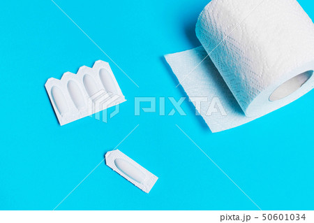 suppository and toilet paper on a blue background, 50601034