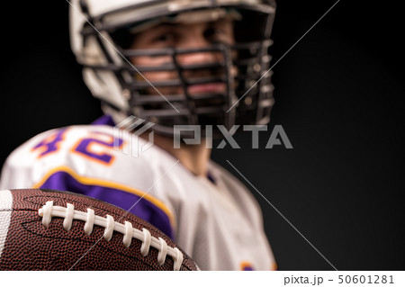 American football player holding the ball in his hands in front of the camera. Concept American American football player holding the ball in his hands in front of the camera. Concept American 50601281