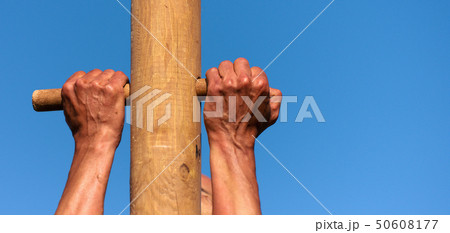 A man climbs onto a pillar, hands detail 50608177