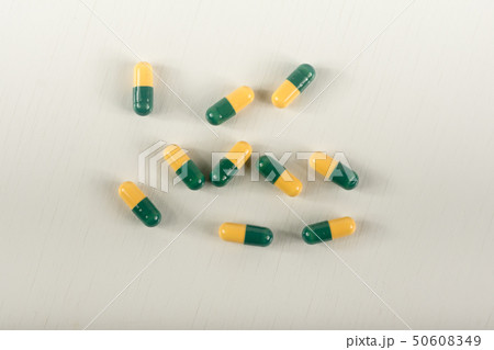 Green, yellow tramadol capsule pills on white. 50608349