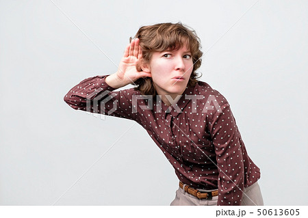 Woman with curly hair placing hand on her ear Woman with curly hair placing hand on her ear 50613605