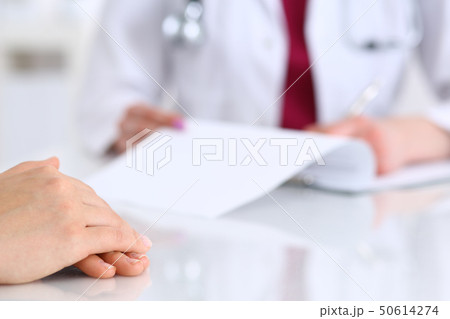 Unknown doctor woman consulting patient while filling up an application form at the desk in hospital Unknown doctor woman consulting patient while filling up an application form at the desk in hospital 50614274