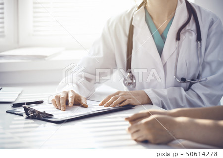 Doctor and patient are discussing something in clinic, just hands at the desk. Medicine and best Doctor and patient are discussing something in clinic, just hands at the desk. Medicine and best 50614278