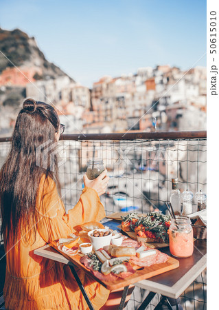 Beautiful woman on breakfast at outdoor cafe with amazing view in Cinque Terre 50615010