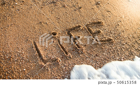 Closeup image of sea waves washing off word Life inscripted on the sand Closeup image of sea waves washing off word Life inscripted on the sand 50615358