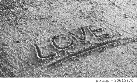 Black and white image of word love written on wet beach sand 50615370