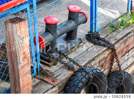 Mooring metal bollard with a tires at the pier 50628358