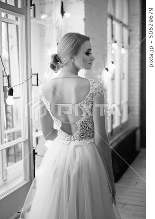 Graceful back of the bride. Looking out the window.Hairstyle - elegant bunch in the French style. Graceful back of the bride. Looking out the window.Hairstyle - elegant bunch in the French style. 50629679