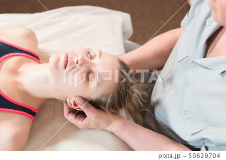 Male manual visceral therapist masseur treats a young female patient. Head and ear massage 50629704