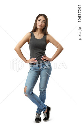 Young woman in gray sleeveless top and blue jeans standing with hands on hips and one leg in front Young woman in gray sleeveless top and blue jeans standing with hands on hips and one leg in front 50637292