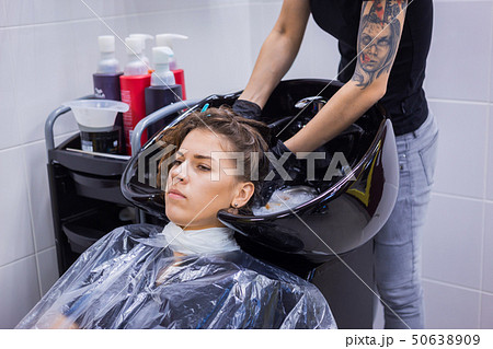 Hairdresser washing hair of woman client Hairdresser washing hair of woman client 50638909