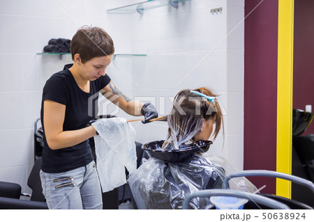 Professional hairdresser coloring hair of woman client at studio Professional hairdresser coloring hair of woman client at studio 50638924