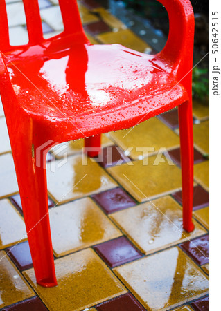 Red plastic garden chairs on the outdoor terrace in the home garden after the rain 50642515