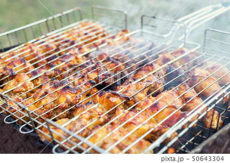 Close-up chicken wings cooking in metal barbecue grid on grill brazier. Outdoors weekend party on Close-up chicken wings cooking in metal barbecue grid on grill brazier. Outdoors weekend party on 50643304