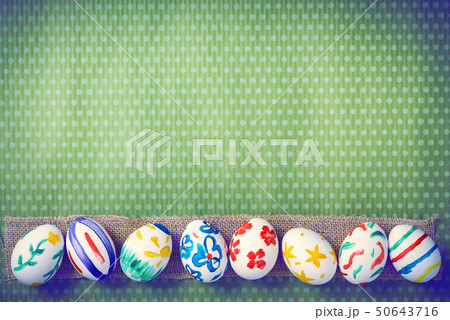 Painted Easter eggs on a green background with white polka dots 50643716