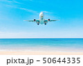 Plane on the blue sky is landing over the ocean 50644335